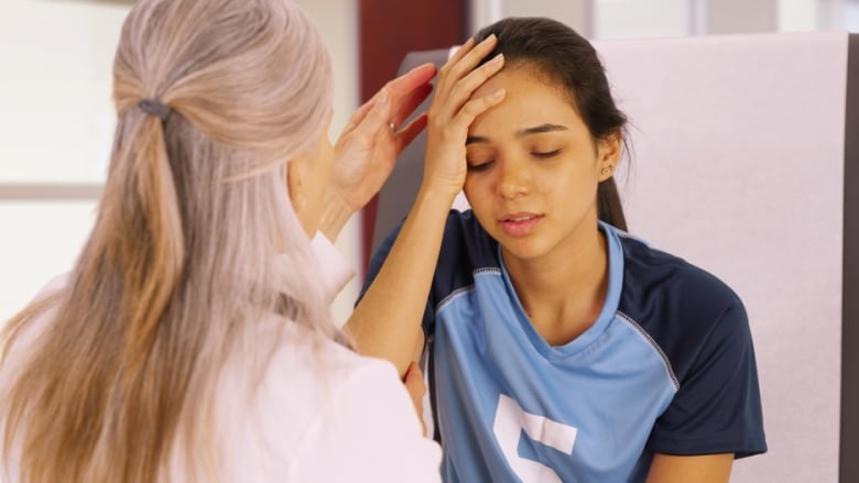 Young soccer player with a head injury is examined by physiotherapist