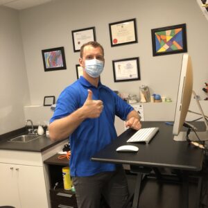 Masked physiotherapist in saskatoon, Pete, gives a thumbs up