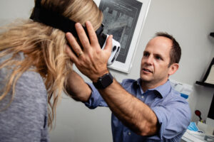 Kregg a physiotherapist using VNG goggles on a client to begin a Vestibular Therapy Assessment and treatment.