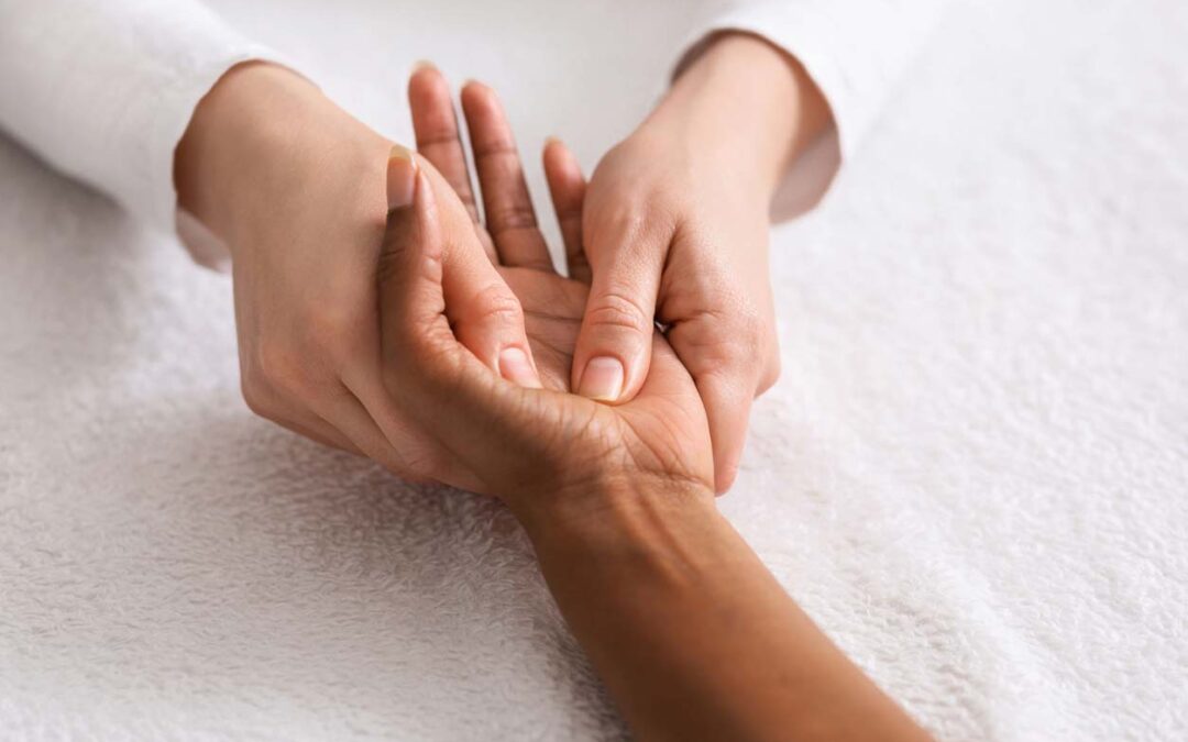 A physiotherapist is performing hand therapy via massage on a clients upturned hand.