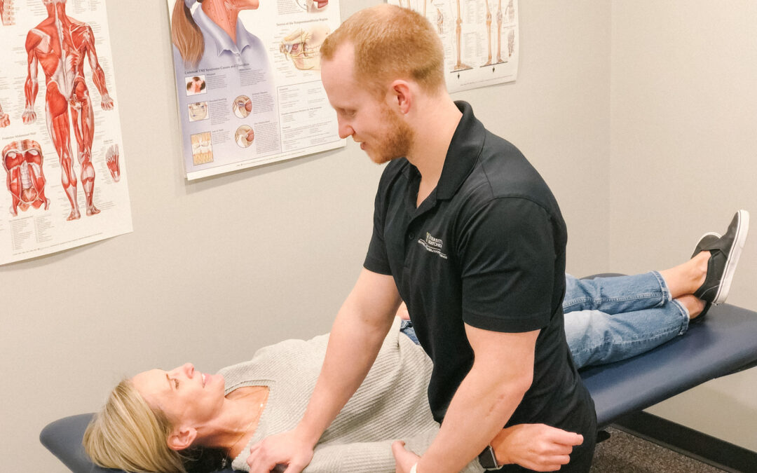 A Physiotherapist performing manual therapy on a client's shoulder as they lay on a client massage table.